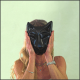 Image of Mary K. holding sister cat mask in diamond black. Portrait facing the viewer.
