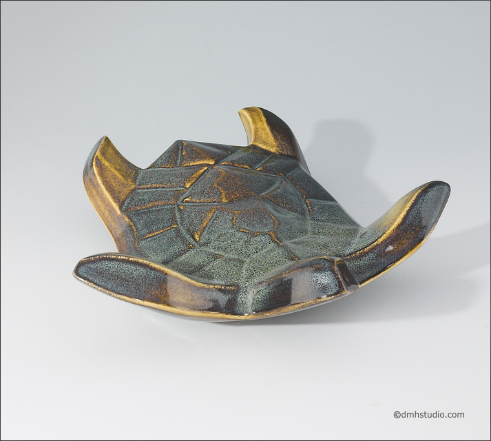 Large image of Flying Sea Turtle sculpture in gold and green glaze, seen slightly from above, landing toward the viewer.
